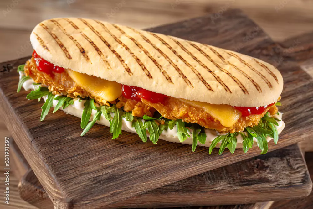 Panini med panerad kyckling, ruccolasallad och ost.